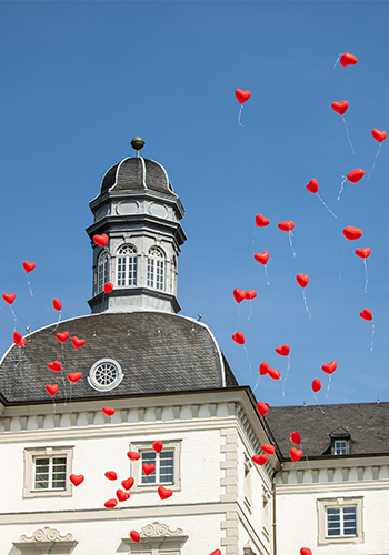 rote Herzen-Ballons fliegen vor Kirche