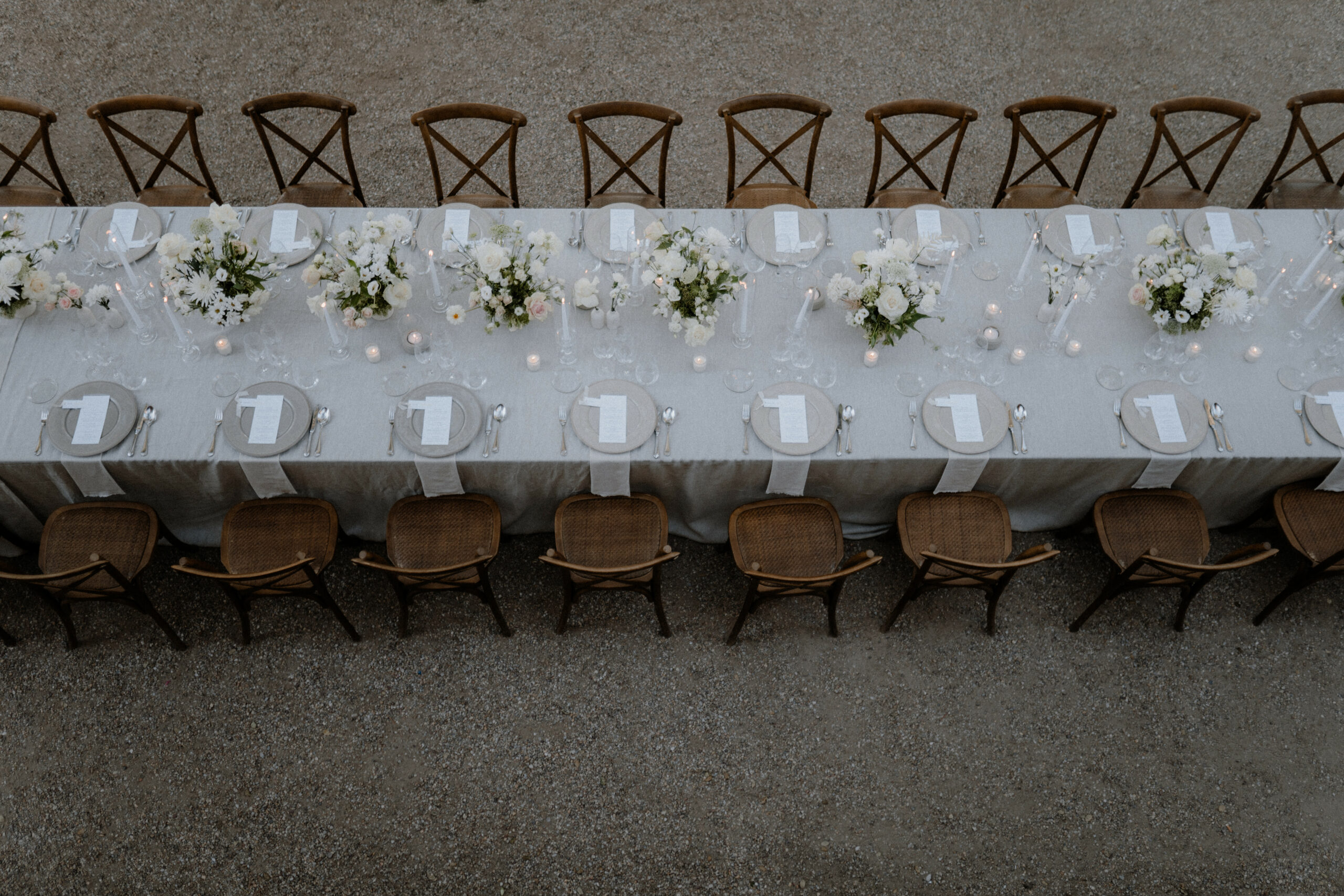 Langer Hochzeitstisch mit weißer Tischdecke und braunen Stühlen aus der