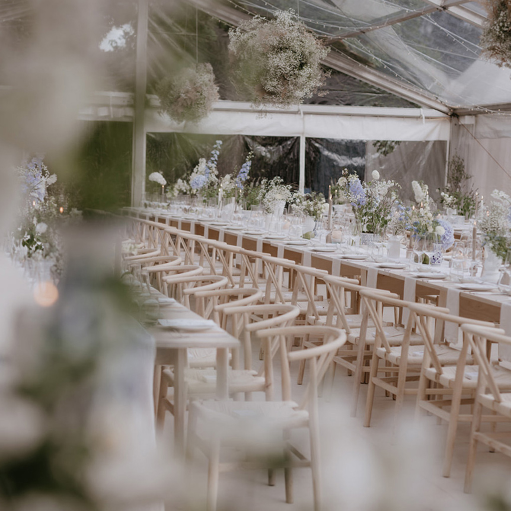 Elegante Hochzeitsfeier in einem klaren Zelt mit wunderschön dekorierten Tischen und modernen Holzstühlen, perfekt für eine stilvolle Hochzeit in Köln, Bonn oder Düsseldorf.