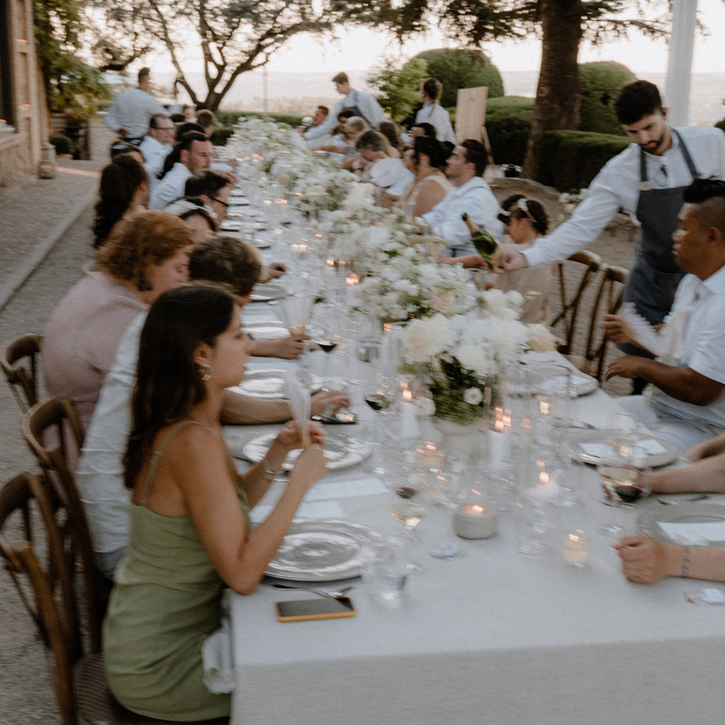 Gäste sitzen an Hochzeitstafel bei Sonnenuntergang