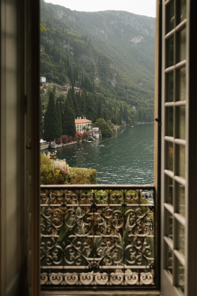 Romantischer Blick vom Balkon auf einen italienischen See, umgeben von Zypressen und historischen Villen – perfekte Kulisse für eine Destination Wedding in Italien.