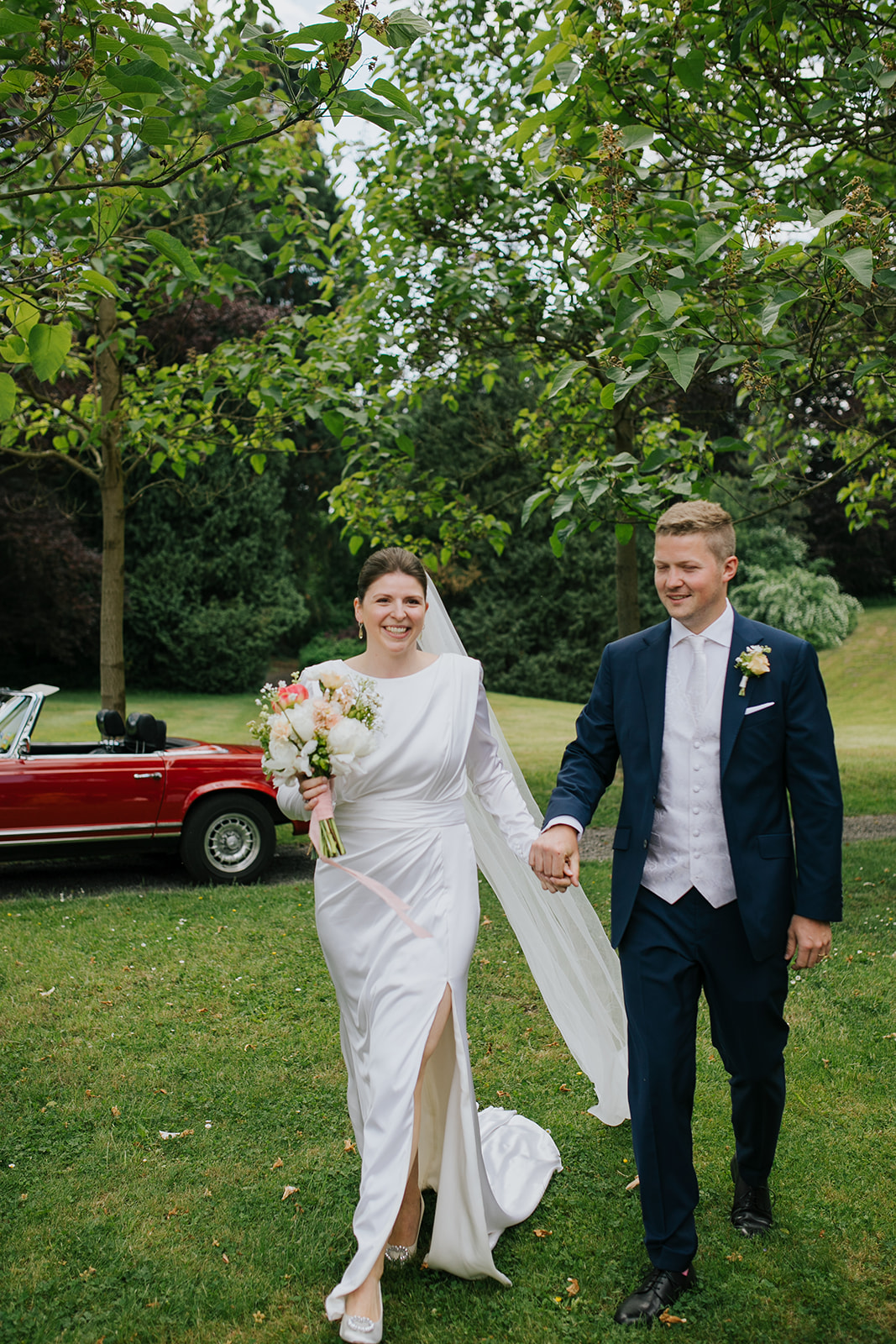 Glückliches Brautpaar mit Oldtimer im Grünen – Hochzeitsplanung und -konzept in NRW