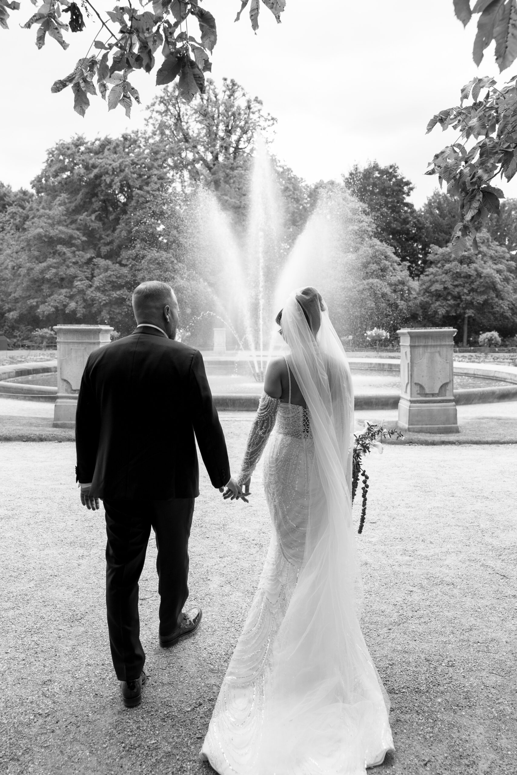 Braut und Bräutigam Hand in Hand vor Brunnen – romantischer Hochzeitsmoment in Köln